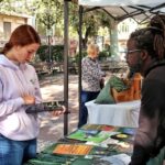 People at an outdoor information booth with displayed materials.