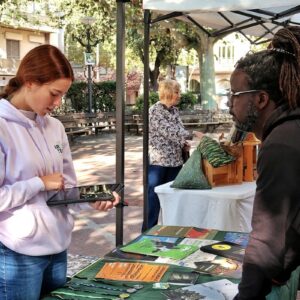 People at an outdoor information booth with displayed materials.