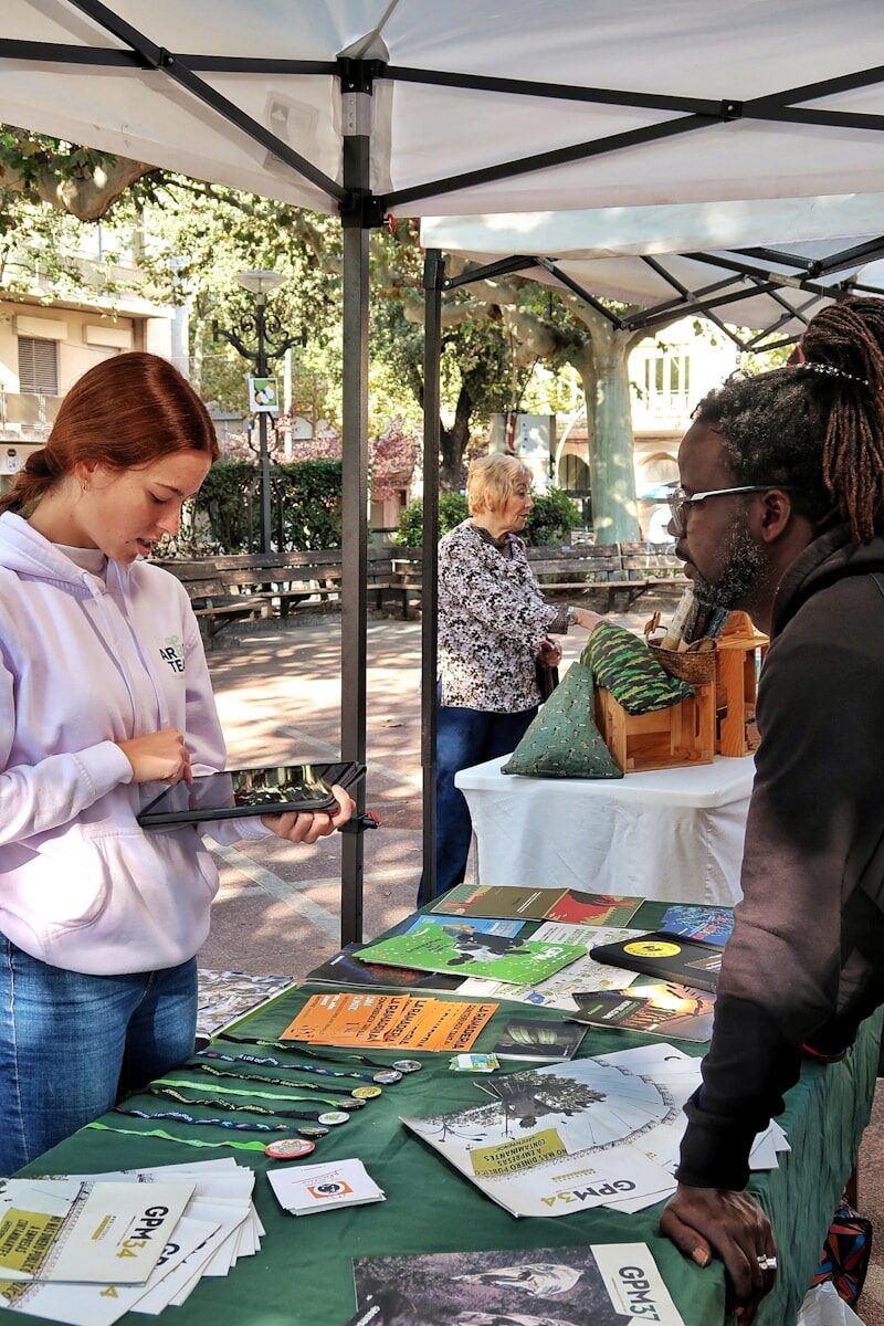 People at an outdoor information booth with displayed materials.